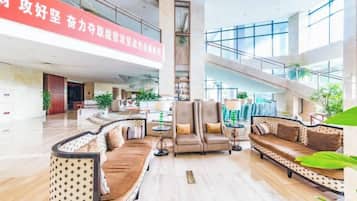 A spacious lobby with a high ceiling, a central staircase, and seating areas with sofas and armchairs.
