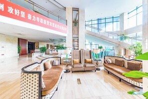 A spacious lobby with a high ceiling, a central staircase, and seating areas with sofas and armchairs. - Doreen Hotel (Lianshui)
