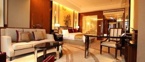 A modern hotel room with a sofa, a dining table, and a bed.