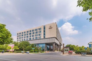 Un hotel de varios pisos con un diseño moderno, que cuenta con una entrada amplia y un estacionamiento.