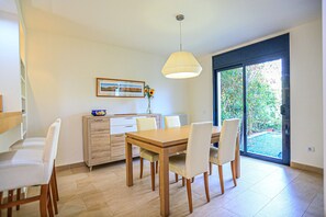 Enjoy meals in this dining area with a table, chairs, and a beautiful view of the garden through the large sliding door.