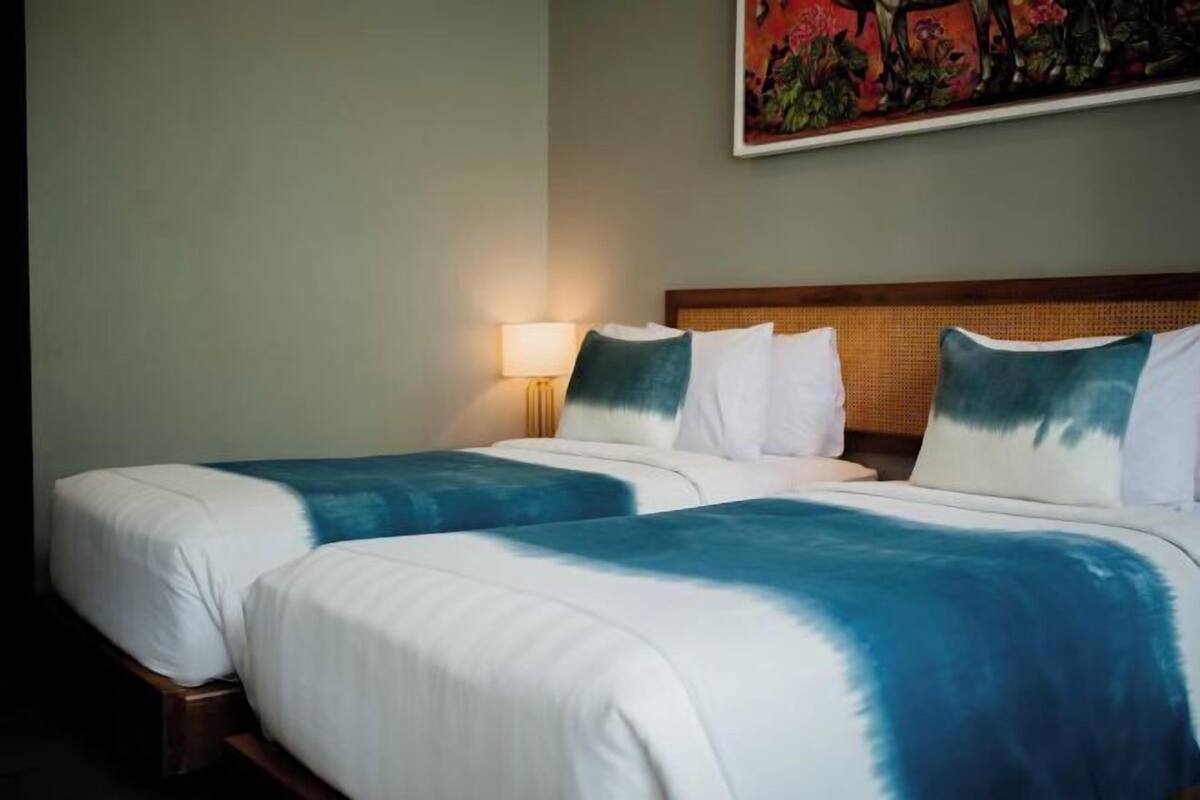 Ein Hotelzimmer mit zwei Betten, einem Kopfteil, einer Lampe und einem Bild an der Wand.