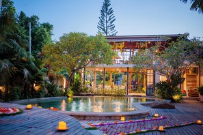 Un bâtiment moderne doté d’une piscine, entouré d’une végétation luxuriante et agrémenté d’une terrasse en bois.
