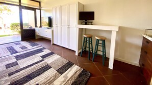 A modern kitchen with white cabinetry, a built-in TV, and two stools. - Stunning ocean view condo (Maunaloa)