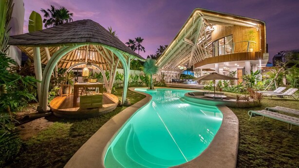 Ein moderner Poolbereich mit außergewöhnlichem architektonischem Design, darunter ein geschwungener Pool und eine überdachte Lounge-Bereich.