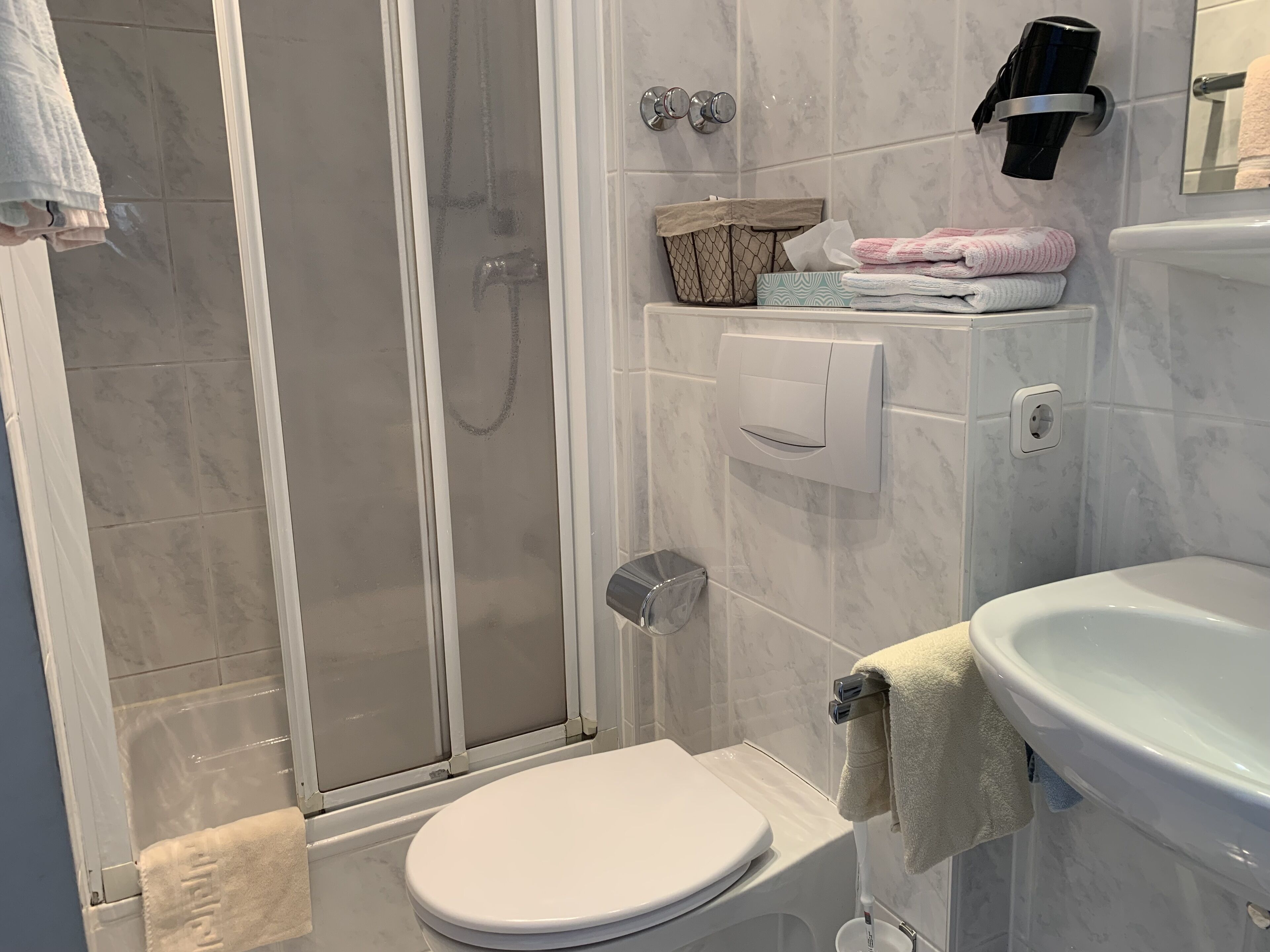 A modern bathroom with a shower, toilet, and sink.
