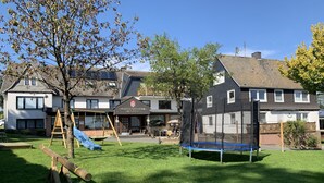 A residential area with a playground, a trampoline, and a building with a sign that reads "Wittgensleiner Schweiz". - Pension Wittgensteiner Schweiz (Bad Berleburg)