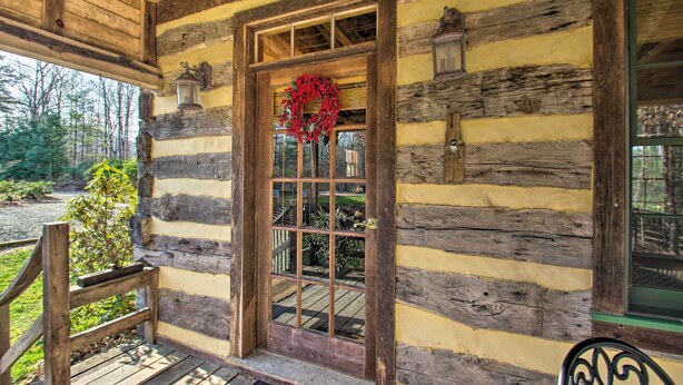 A log cabin with a wooden door, a wreath, and a lantern on the wall. - Numerous On-Site Trails: Earlysville Wooded Cabin (Earlysville)