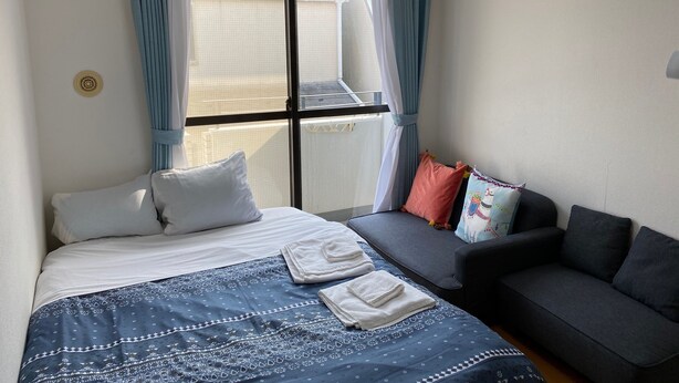 A hotel room with a bed, a sofa, and a window with curtains. - White Terrace Sakurashinmachi (Tokyo)