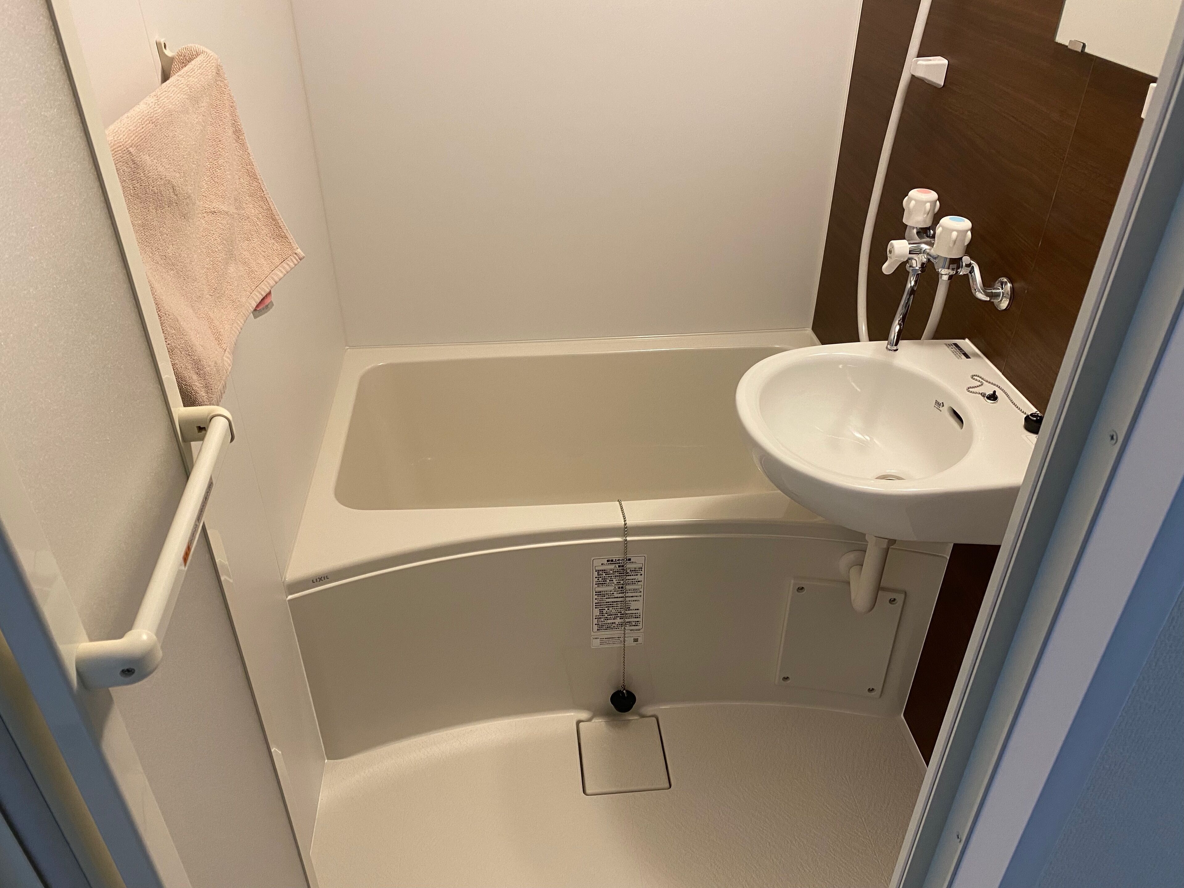A small bathroom with a bathtub, sink, and towel rack.