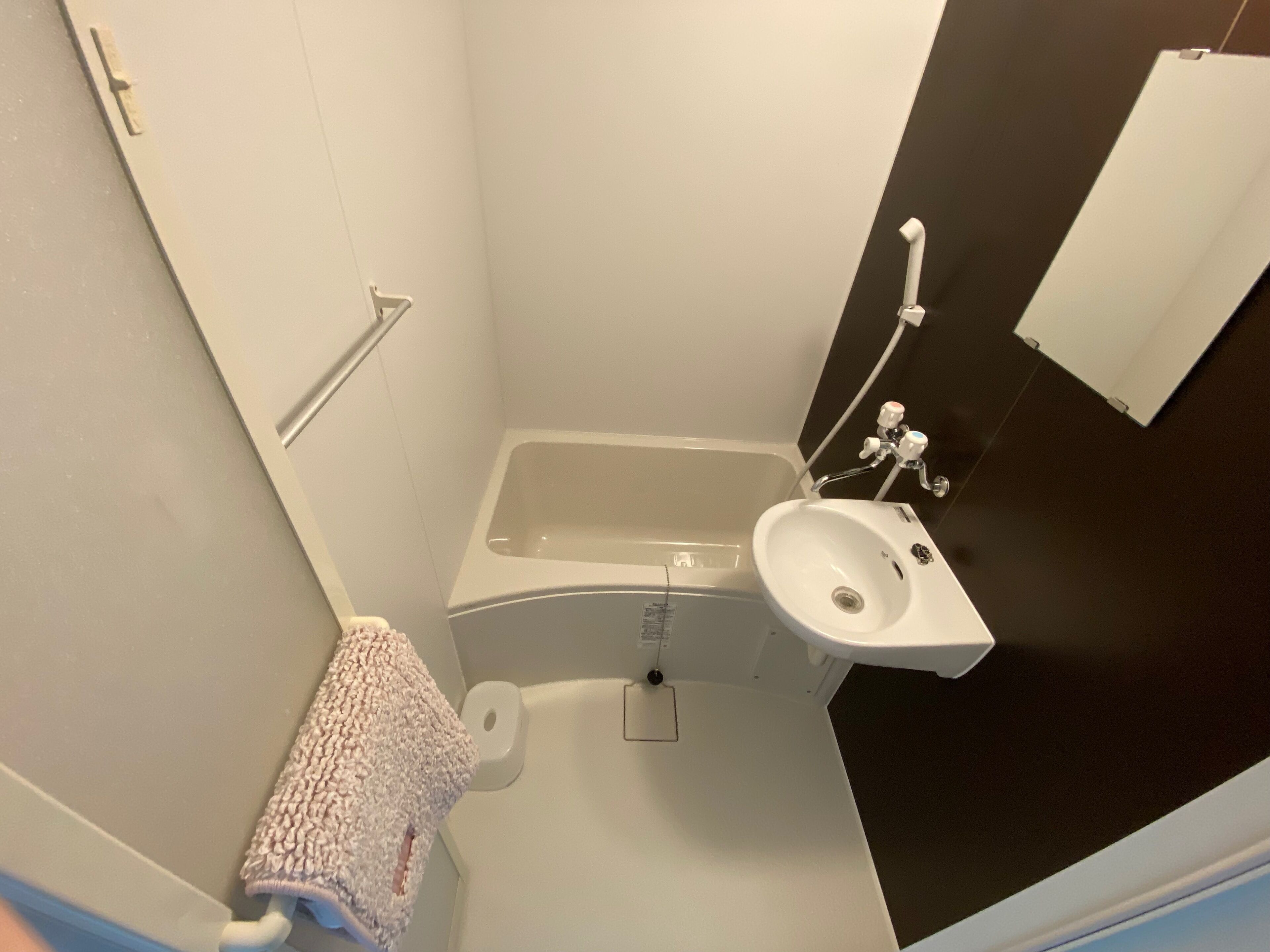 A small bathroom with a bathtub, a sink, and a towel hanging on the wall.