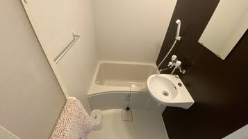 A small bathroom with a bathtub, a sink, and a towel hanging on the wall.
