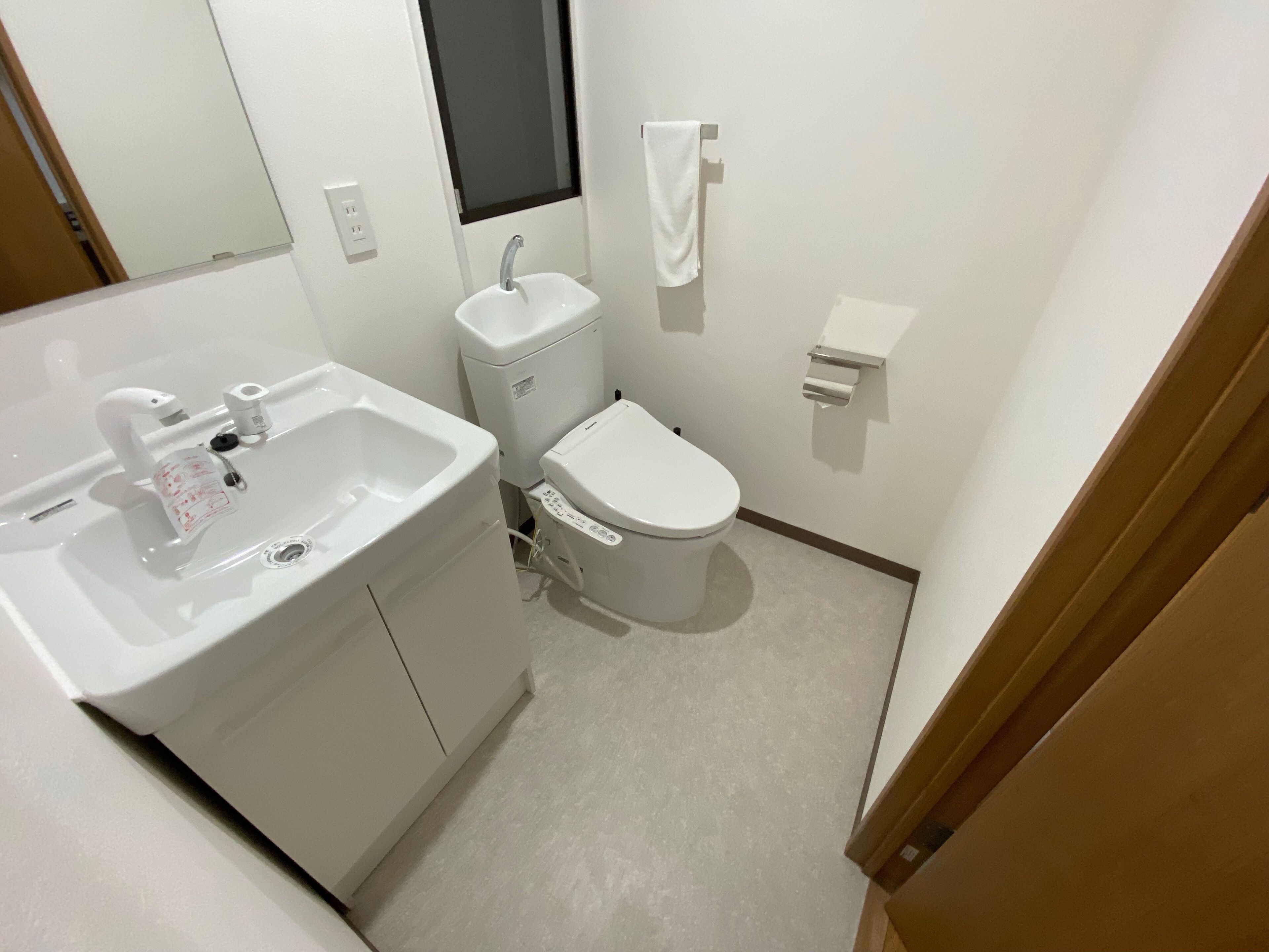 A small, clean bathroom with a white sink, toilet, and mirror.