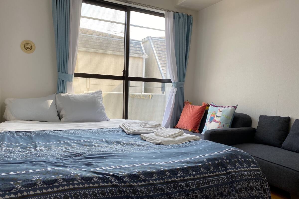 A bedroom with a bed, a sofa, and a window with curtains.