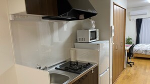 A compact kitchen with a gas stove, a microwave, and a refrigerator. - White Terrace Sakurashinmachi (Tokyo)