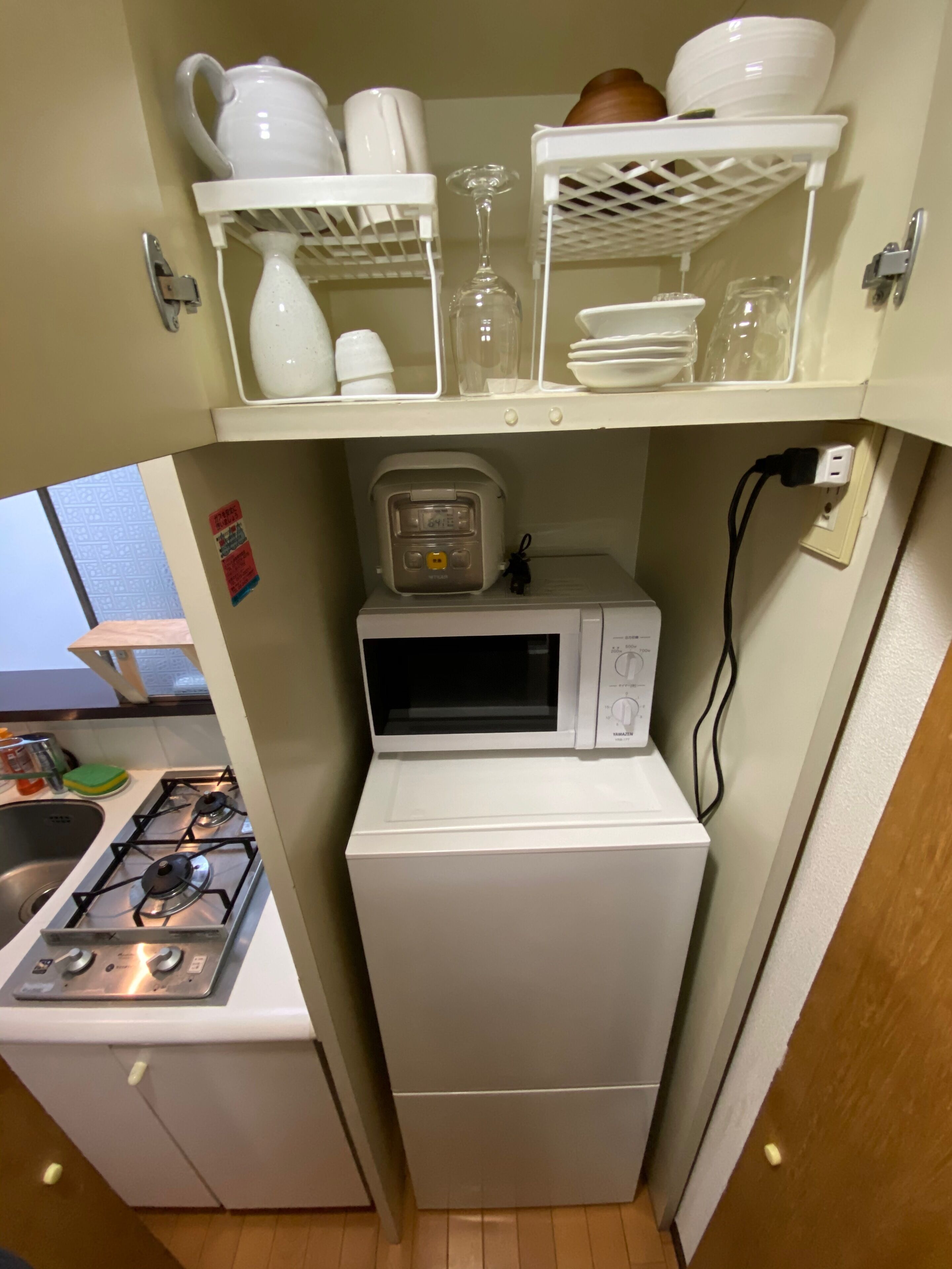 A compact kitchen with a microwave, a small refrigerator, and a gas stove.