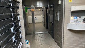 A hotel corridor with a reception desk, a vending machine, and a door leading to a bathroom. - White Terrace Sakurashinmachi (Tokyo)