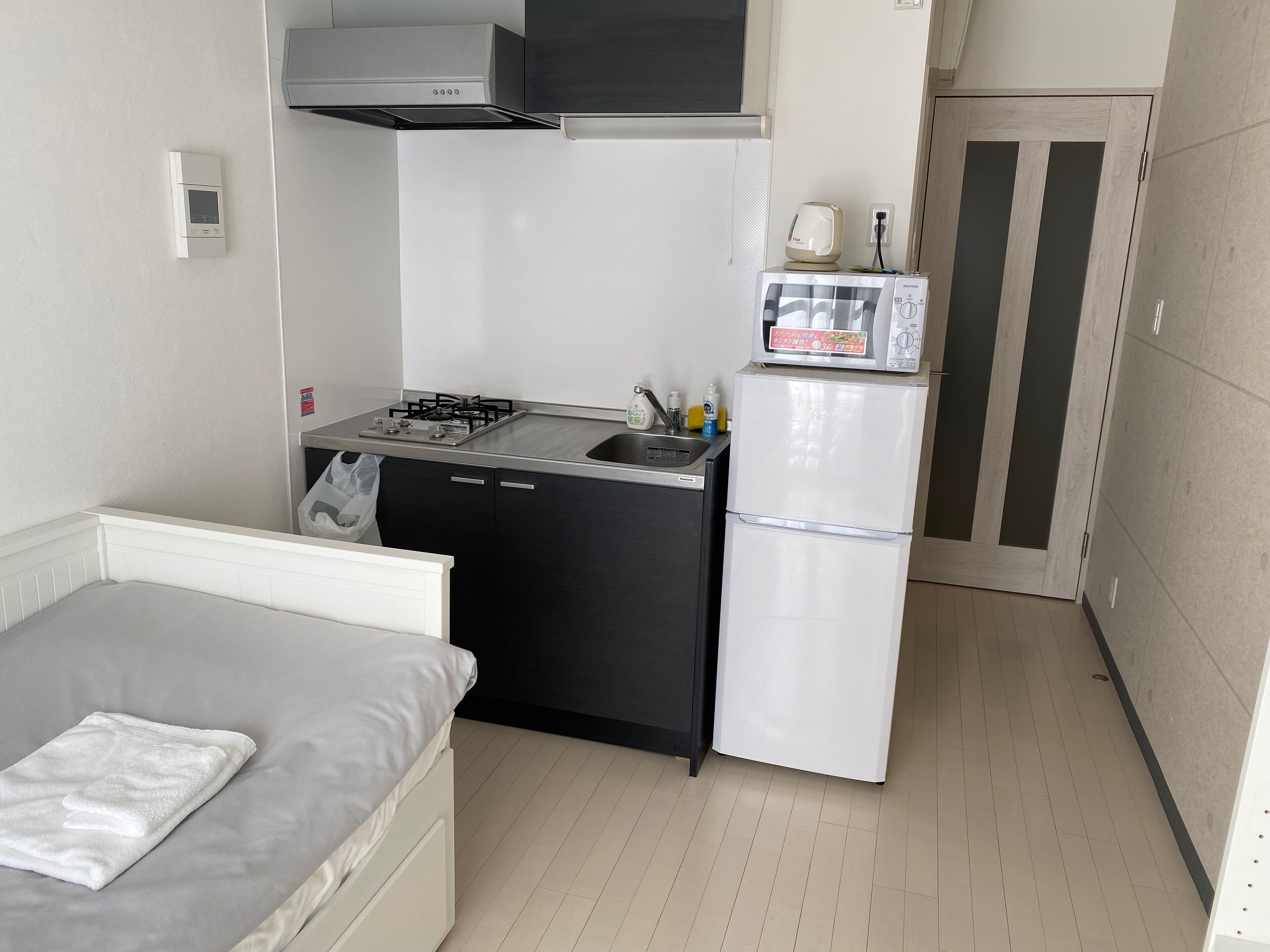A compact kitchenette with a gas stove, sink, and a microwave on a small fridge.