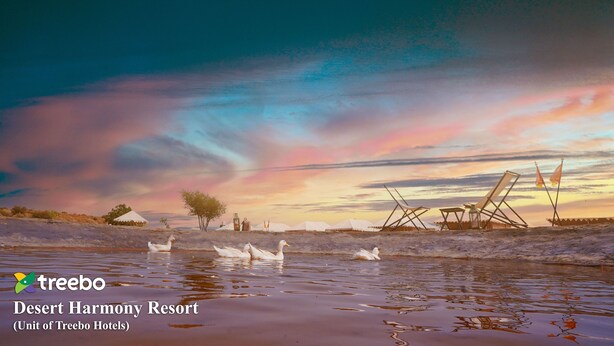 A serene lakeside view at Desert Harmony Resort with swans, a tent, and a unique metal structure. - Treebo Desert Harmony Camp (Jaisalmer)