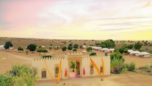 Desert Harmony Resort with a traditional architectural entrance, surrounded by desert landscape and sparse vegetation. - Treebo Desert Harmony Camp (Jaisalmer)
