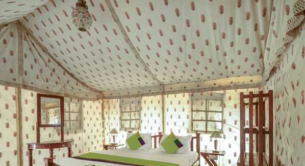 A room with a bed, wooden furniture, patterned wallpaper, and a hanging lantern. - Treebo Desert Harmony Camp (Jaisalmer)