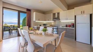 Une cuisine moderne avec un coin repas, de grandes fenêtres et une vue sur l’extérieur.
