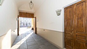 A hallway with a wooden door, a light fixture, and a view of buildings outside. - GuestHost - Comfortable apartment that can accommodate up to 4 people with great ease and is equipped with every kind of comfort. We are in the beating heart of Turin, Piazza Vittorio Veneto, overlooking the Turin hill and the Gran Madre, everything is c (Turin)