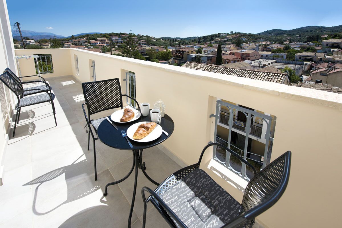 A balcony with two chairs, a table, and a view of a town.