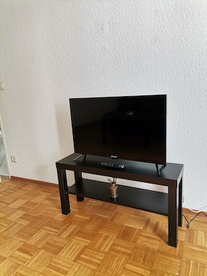 A black entertainment unit with a flat-screen TV, a remote control, and a decorative vase. - 2 bedroom apartment in hanover (Hannover)
