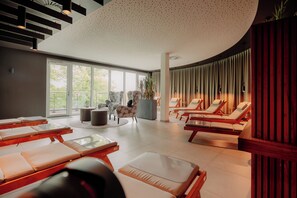 A modern spa with sun loungers, a large window, and a unique ceiling design. - VIA PLAZA Meppen by Hackmann (Meppen)