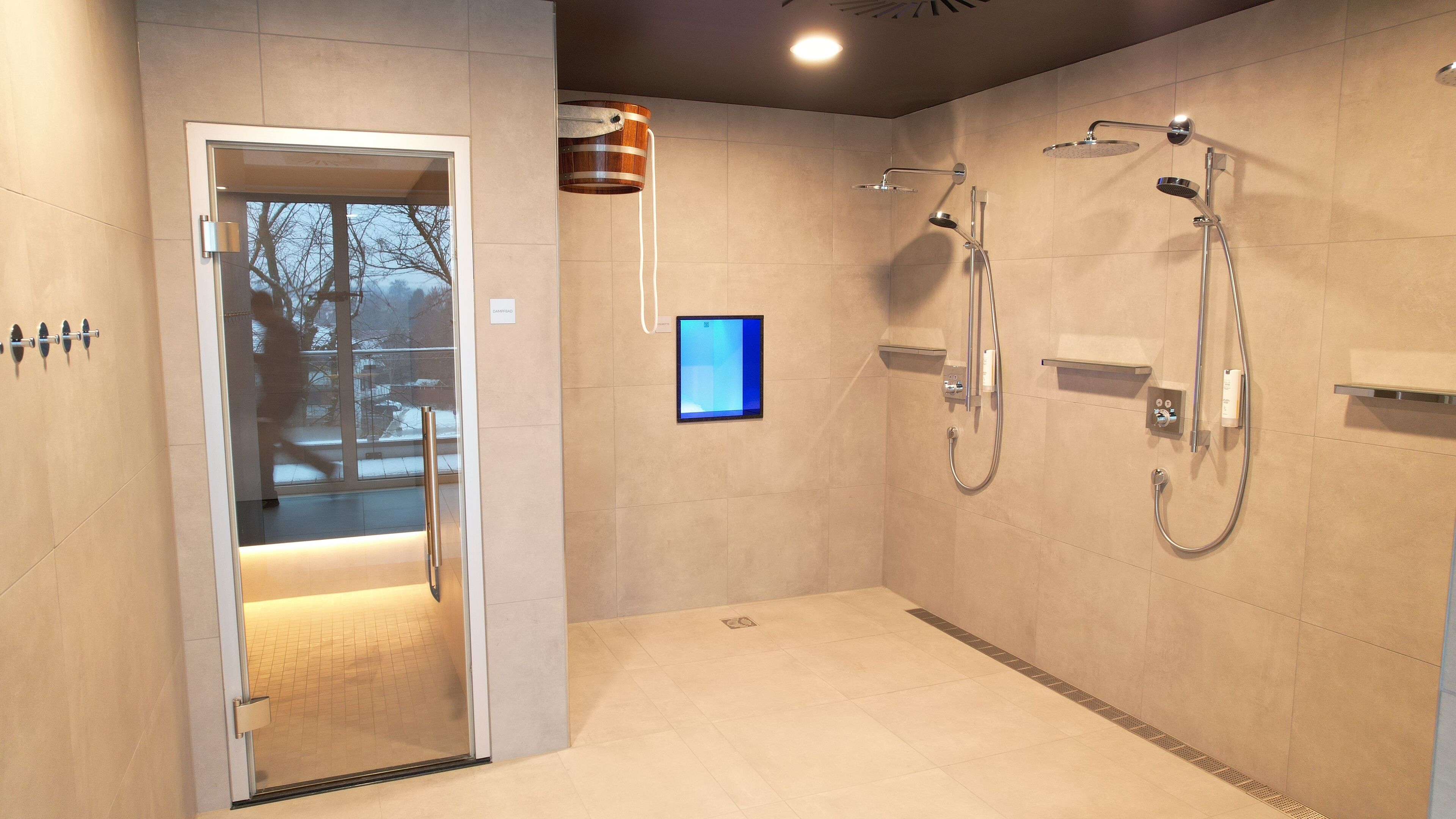 Een moderne badkamer met een glazen douchedeur, een douchegedeelte met meerdere voorzieningen en een digitaal bedieningspaneel.