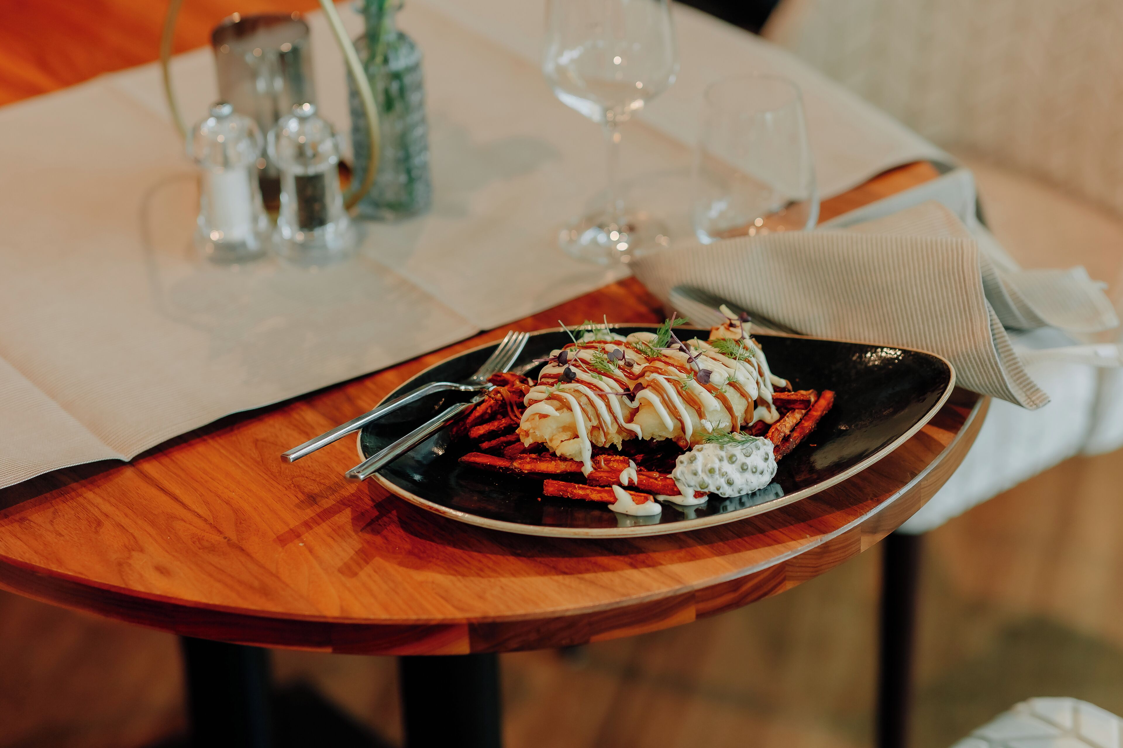 A dining table with a plate of food, a wine glass, and salt and pepper shakers.