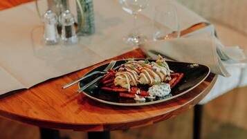 A dining table with a plate of food, a wine glass, and salt and pepper shakers.