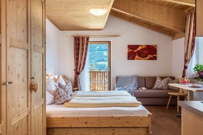 Une pièce en bois comprenant un lit, un canapé, une table à manger et une fenêtre donnant sur un paysage agréable.