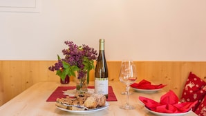 Une table en bois avec une bouteille de vin, un verre, des assiettes remplies de nourriture et un vase de fleurs.