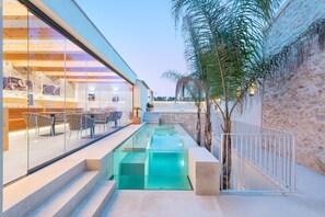 Una piscina al aire libre, sombrillas, sillones reclinables de piscina
