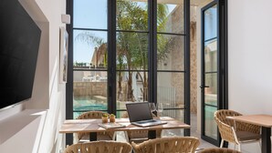 A modern outdoor dining area with wicker chairs, a laptop, and a glass table. - Placeta Vella Turismo de Interior (Selva)