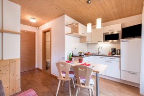 Una cocina moderna con armarios blancos, suelo de madera y luces colgantes.