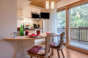 Una cucina moderna con zona pranzo, pavimento in legno e un'ampia finestra vista su del verde.