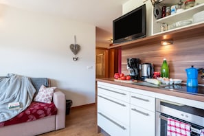 A compact kitchen with a flat-screen TV, a coffee maker, and a toaster.