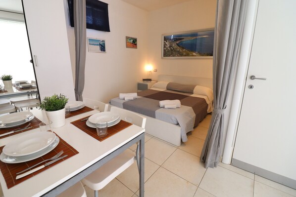 Quarto de hotel com cama, mesa de cabeceira, abajur e um quadro na parede.