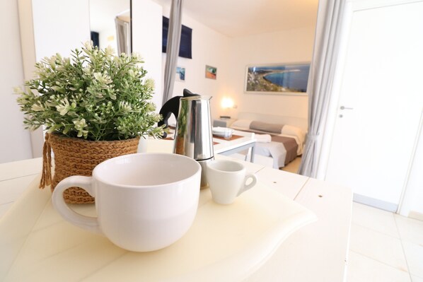A table with a white mug, a white cup, and a woven basket with green plants.