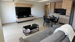 A modern living room with a sofa, a coffee table, a TV, and a dining area with chairs and a table. - Charming F2 completely renovated in the center of CAVALAIRE SUR MER (CAVALAIRE SUR MER)