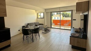 A spacious living area with a dining table, sofa, and a sliding glass door leading to an outdoor patio. - Charming F2 completely renovated in the center of CAVALAIRE SUR MER (CAVALAIRE SUR MER)