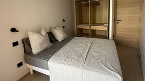 A bedroom with a bed, a wardrobe, and an air conditioning unit. - Charming F2 completely renovated in the center of CAVALAIRE SUR MER (CAVALAIRE SUR MER)