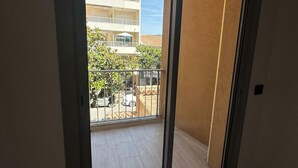 A room with a sliding glass door leading to a balcony with a view of a building and a parked car. - Charming F2 completely renovated in the center of CAVALAIRE SUR MER (CAVALAIRE SUR MER)