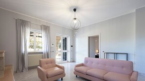 Un salon spacieux avec un canapé beige, un fauteuil assorti et un luminaire suspendu moderne.