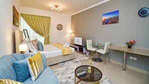 A modern hotel room with a bed, sofa, TV, and a dining area. - Cozy Studio - Goldcrest Executives JLT - NLN (Dubai)