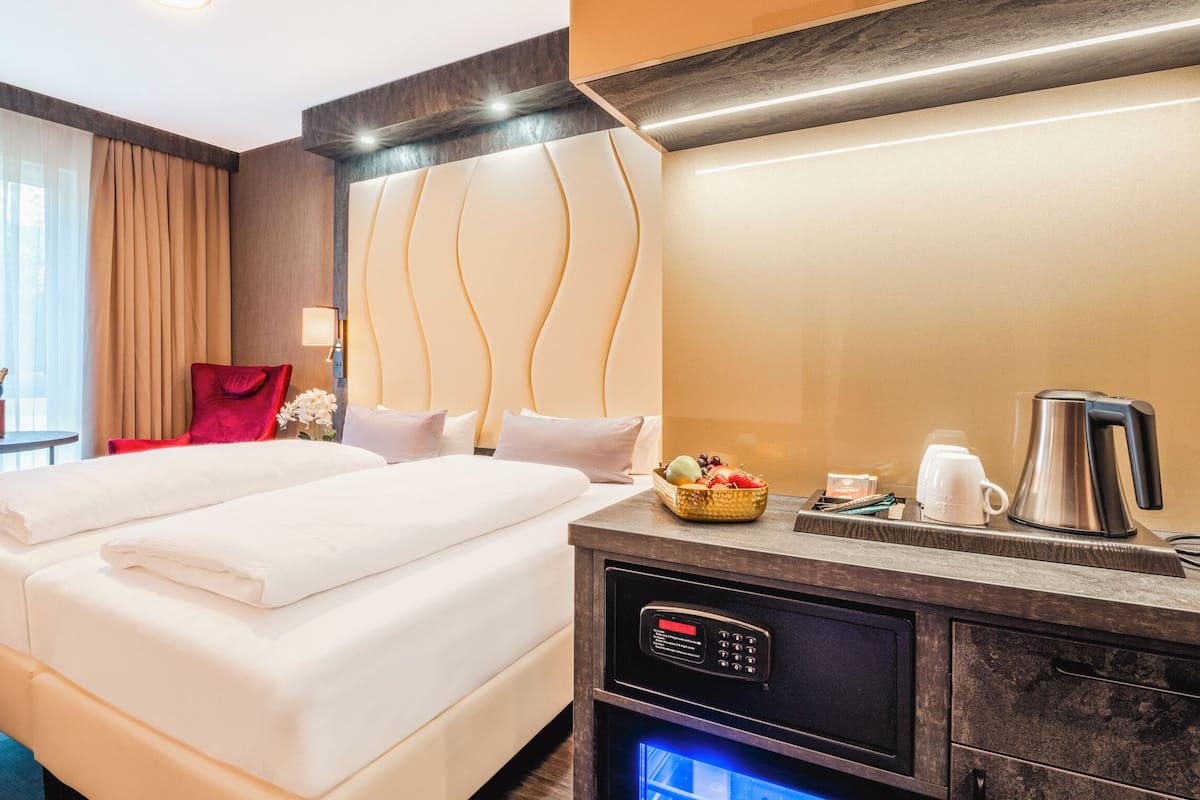 Una habitación de hotel con cama, mesita de noche, lámpara y cafetera.