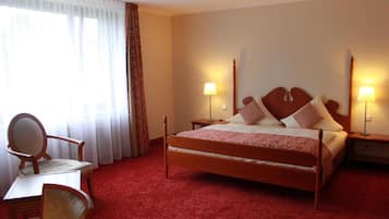 Ein Hotelzimmer mit einem Holzbett, zwei Nachttischlampen, einem Sessel und einem Tisch.